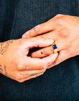 Close-up of hands with a ring featuring a blue gemstone against a dark background