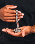 Person holding a silver chain in their hands against a black background